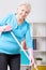 Elderly woman sweeping floor