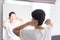 Elderly woman using comb with her hair in front of mirror,Backview