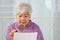 Elderly woman using a magnifying glass to reading through the lens to handheld document as her eyesight deteriorates with age