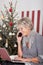 Elderly woman using telephone on Christmas Eve
