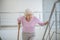 Elderly woman with a walking stick slowly going upstairs