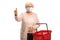 Elderly woman wearing a face medical mask showing a thumb up sign and holding a shopping basket