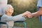 Elderly woman, wheelchair and caregiver holding hands for support, care and solidarity in nature park. Senior person