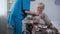 Elderly woman in wheelchair feeling headache, asking nurse for painkillers