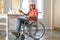 Elderly woman in wheelchair after stroke drinks orange juice