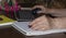 An elderly woman works on a computer and writes in a notebook