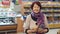 An elderly woman with wrinkles on her face chooses products in the supermarket.