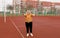 An elderly woman in a yellow jacket is doing sports exercises on a red treadmill. the stadium is a healthy lifestyle. retired