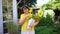 An elderly woman in a yellow top with a bunch of sunflowers in a watering can.