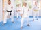 Elderly women and men in kimonos stand in a fighting stance during group karate training session