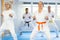 Elderly women and men in kimonos stand in a fighting stance during group karate training session