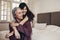 Elderly women sitting on bed with her daughter holding her hands. Smiling mother and daughter sitting at home spending time