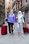 Elderly women strolling with luggage along city street