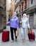 Elderly women strolling with luggage along city street