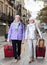 Elderly women strolling with luggage along city street