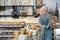 Elderly worker in ceramics factory carries many different clay ceramic cups and plates in cart