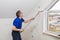 Elderly worker painting wall with glue