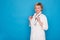 Eldery caucasian doctor lady in white coat and ith stethoscope on blue background. Emotional portraits