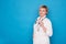 Eldery caucasian doctor lady in white coat and ith stethoscope on blue background. Emotional portraits