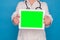 Eldery caucasian doctor lady in white coat and with stethoscope and tablet on blue background. Chroma key screen on tablet