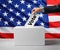 Election in USA. Man putting his vote into ballot box and American flag on background, closeup