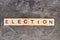 Election word written on wood block, on gray concrete background. Top view.