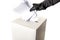 Electoral fraud and hacked elections concept with a hand wearing a leather glove and stuffing a ballot box isolated on white