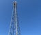 Electric antenna and communication transmitter tower in a northern european landscape against a blue sky