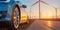 An Electric Car Glides Past A Wind Turbine Farm, Embracing Renewable Energy