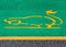 Electric car parking and charging sign. Yellow electric vehicle with plug painted on green background in the asphalt