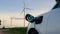 Electric car recharging energy from charging station in wind turbine farm.Peruse