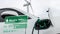 Electric car recharging energy from charging station in wind turbine farm.Peruse