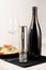 Electric corkscrew in gray metal. There is a bottle of wine, a plate of pasta, a glass and cutlery on the table next to it