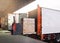 Electric Forklift Loading Shipment Boxes into Cargo Container. Cargo Trailer Truck Parked Loading at Dock Warehouse.