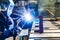 An electric and gas welder in an electromechanical workshop welds a metal structure at a mechanical assembly site