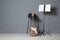 Electric guitar, chair and note stand with music sheets near grey wall indoors.