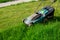 Electric lawn mower Makita. The green lawn is mowed with a lawn mower. A half-mown lawn. The concept of a beautiful manicured lawn