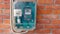 An electric meter on a brick wall that measures energy consumption. Watt-hour measurement tool on brick wall, green with