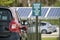 Electric plug-in car charging with electricity from solar renewable power source parked on city street