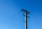Electric pole with a linear wire against the blue sky close-up. Power electric pole
