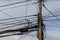 Electric pole with messy wires and cables on blue sky background