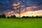 Electric power line in a green field with cloudy sky