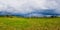 Electric power transmission pole in the mountains with cables along a wooden rail fence leading to the village. Panoramic