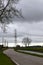 Electric pylon, tree and house along the river and the road in the countryside on a rainy day.