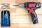 Electric screwdriver with bits and drills on wooden background