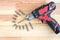 Electric screwdriver with bits and drills on wooden background