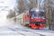 Electric suburban train drives passing by through a snowy park