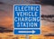 Electric Vehicle Charging Station Sign with Sunset Sky