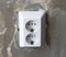 An electric white socket on a gray wall