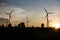 Electric wind turbines farm silhouettes on sun background